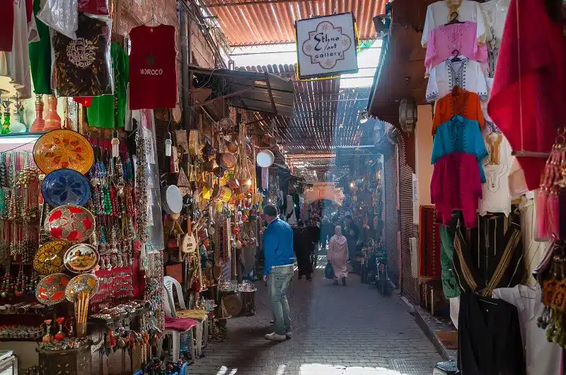 a person walking down a street with persony items on the wall in Cultural Encounters in Morocco