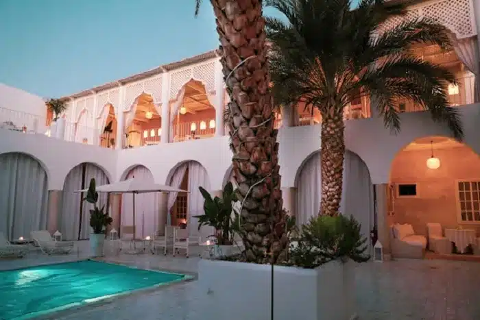 a building with palm trees and a pool while you Immerse in Rich Culture as The Essence of Marrakech Holidays 